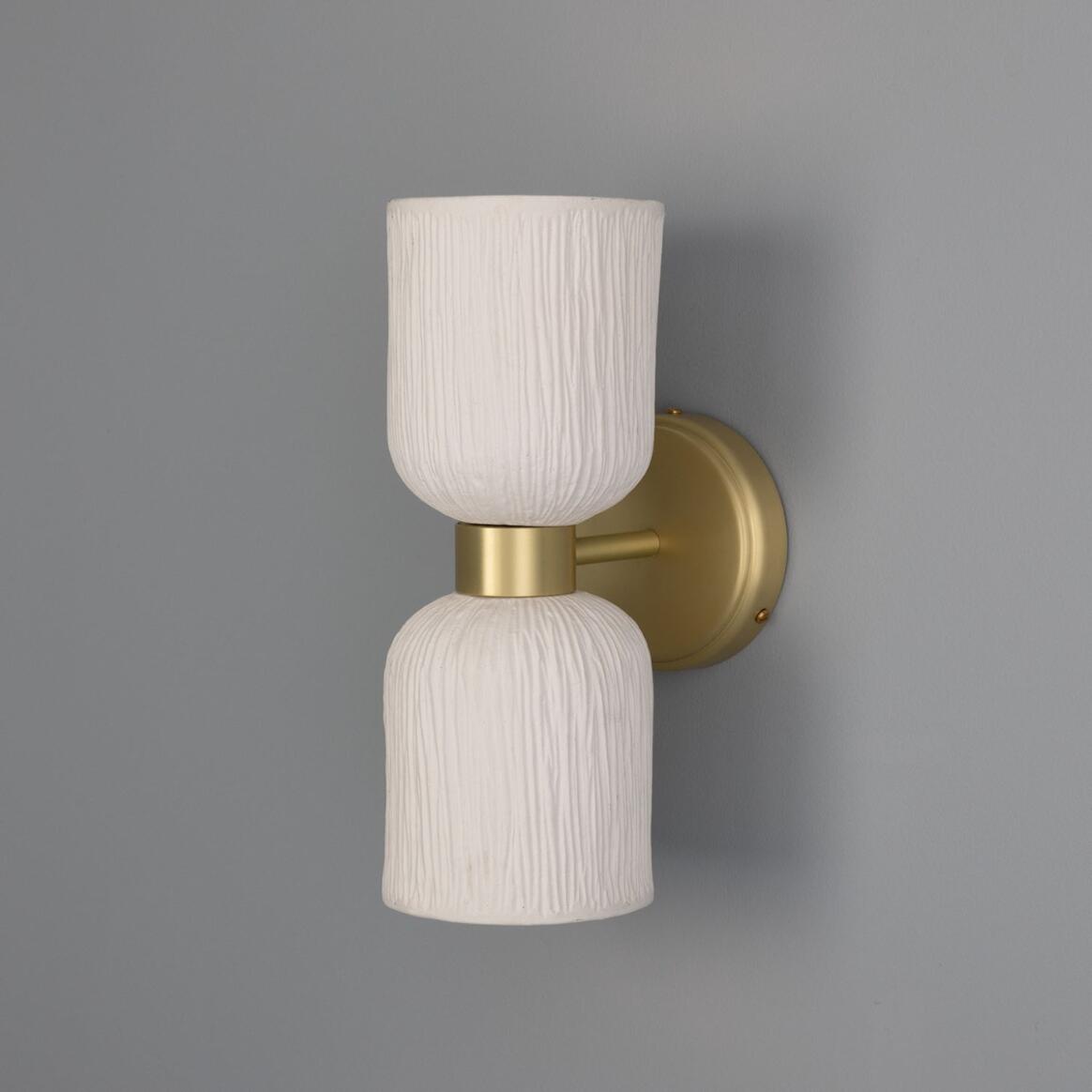 Wall-mounted light fixture with white textured design and gold fixture on a gray background