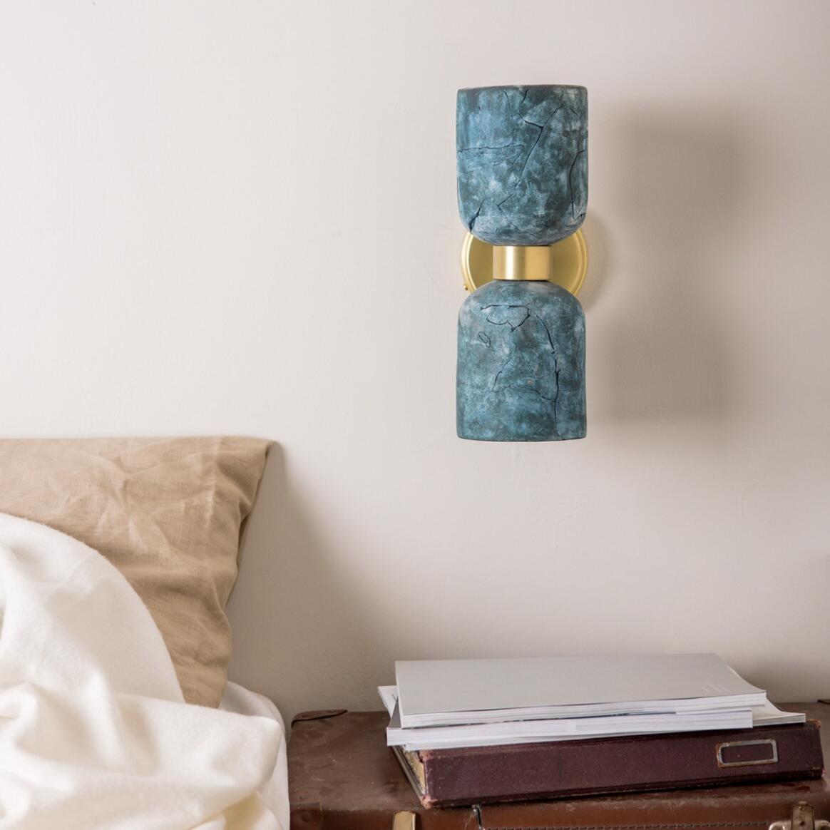 Wall-mounted lamp with blue marble finish and gold base on a neutral wall.