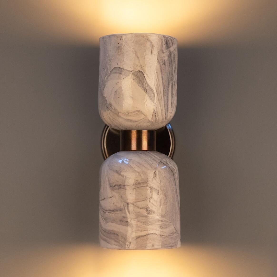 Marble-textured wall sconce with warm glow on a dark background