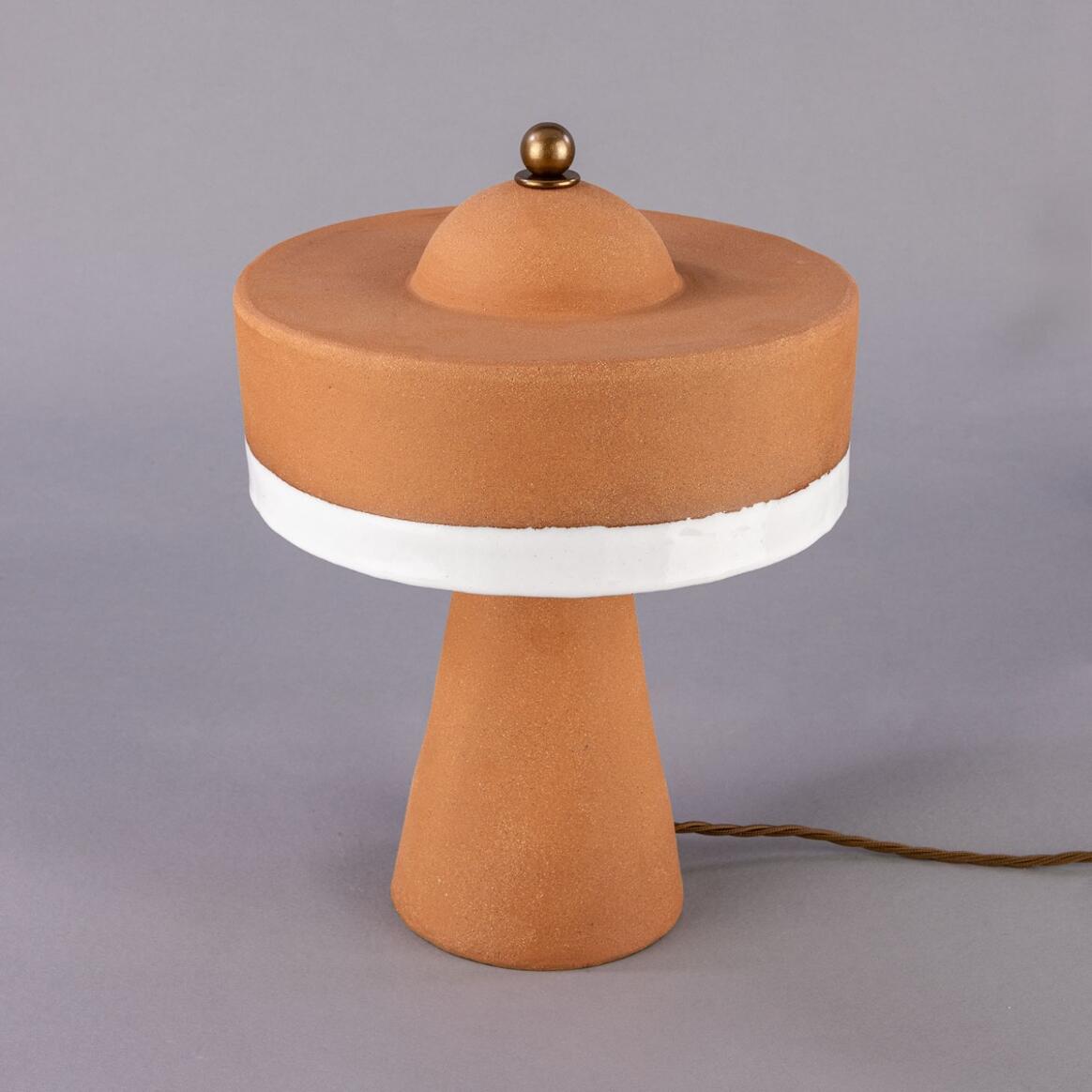 Terracotta-colored table lamp with a white base on a gray background