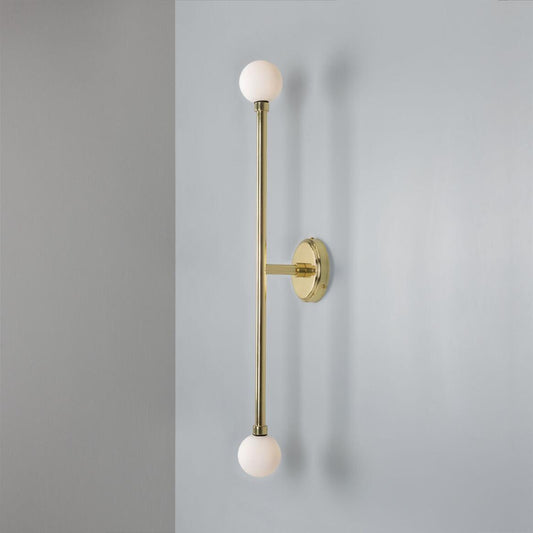 Wall-mounted light fixture with gold finish and white spherical bulbs on a gray background