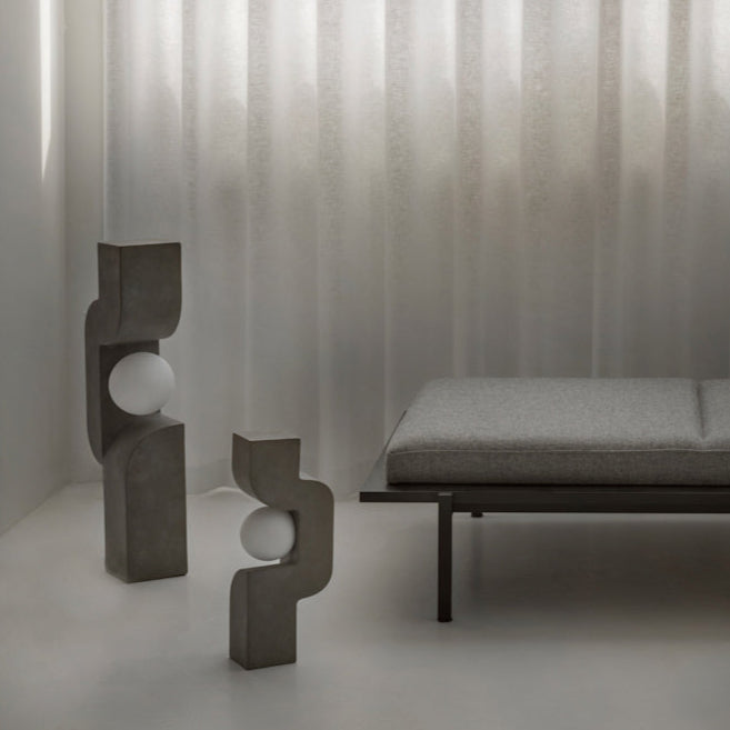 Sitting Man Table Lamp by 101 Copenhagen featuring a sculpted figure seated with an overhead light source on a minimalist table.