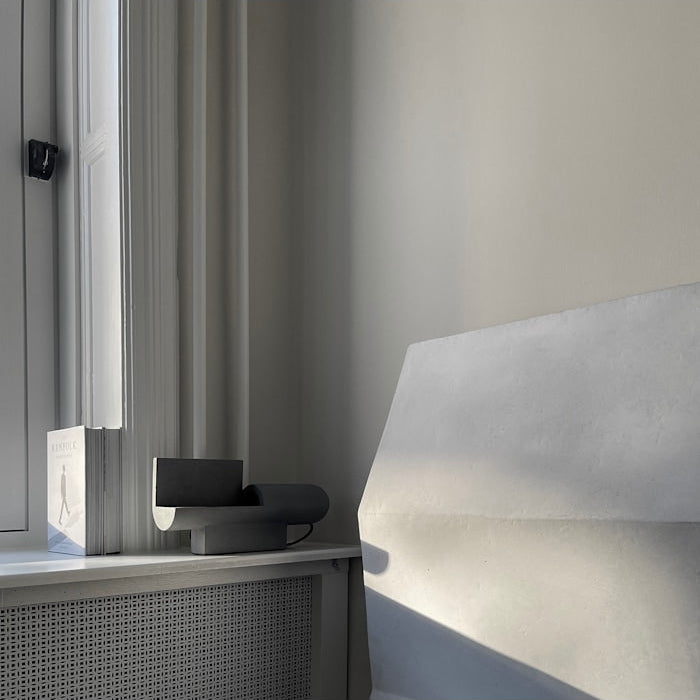 Brutalist Lamp by 101 Copenhagen glowing warmly in a dim room, highlighting its raw surface and moody ambiance