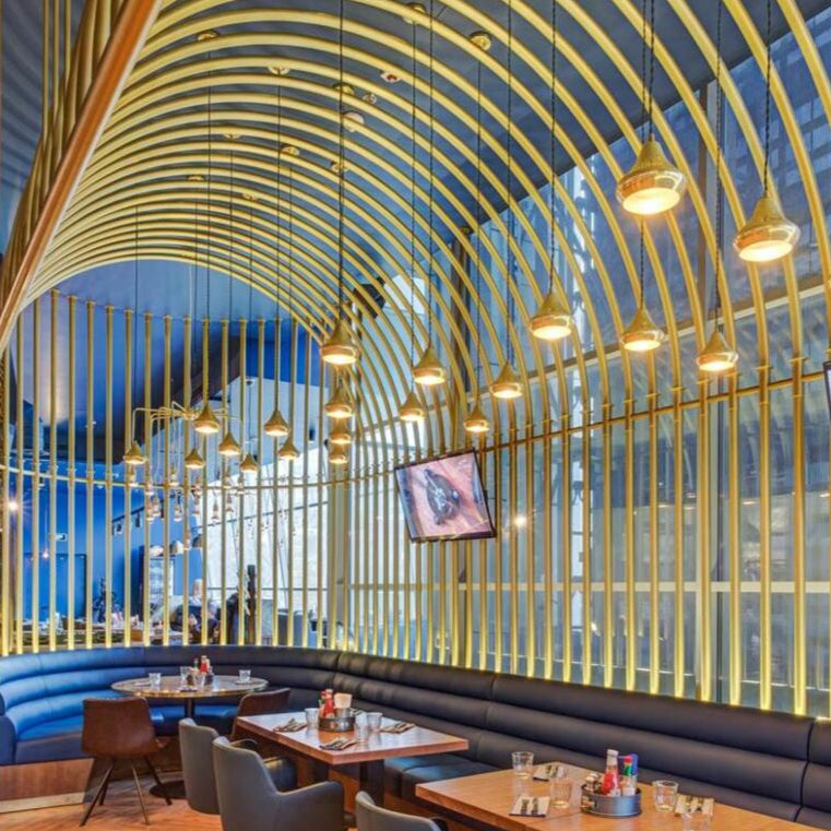 Modern restaurant interior with curved wall design, wooden flooring, and tables with chairs.