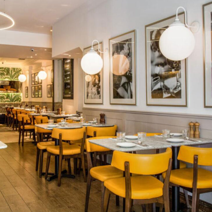 Modern restaurant interior with yellow chairs and tables, framed pictures on the wall, and 'mullan' branding.
