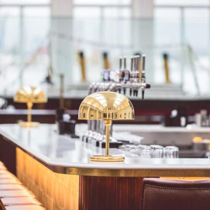 Modern bar interior with a gold lamp and leather chairs, featuring the brand 'Mullan'.